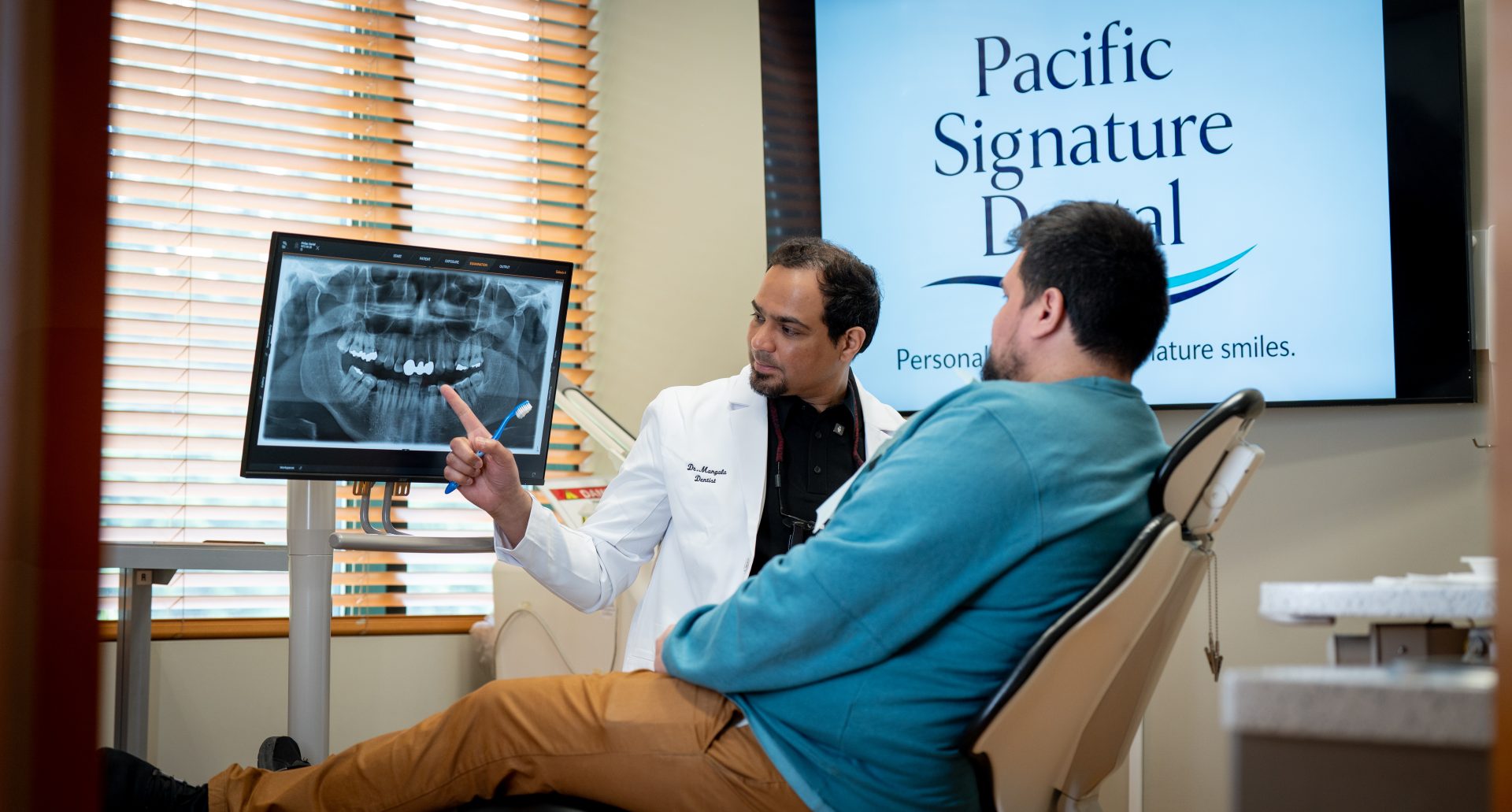 Dr. Mangala reviewing a digital X-ray with a patient at Pacific Signature Dental in Vancouver