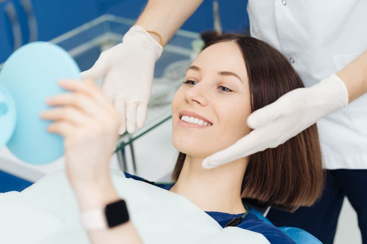 Patient admiring her smile in a mirror after treatment