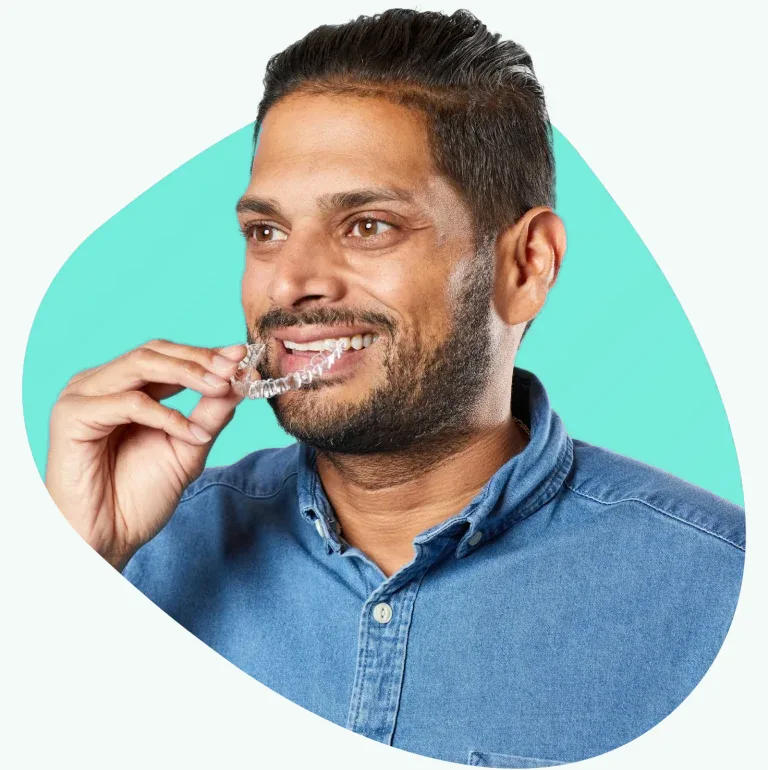 Smiling patient placing a SureSmile clear aligner